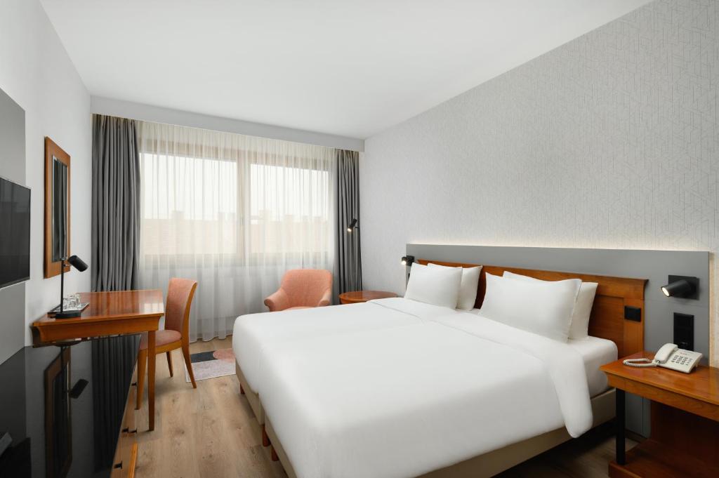 a hotel room with a large white bed and a desk at Danubius Hotel Hungaria City Center in Budapest