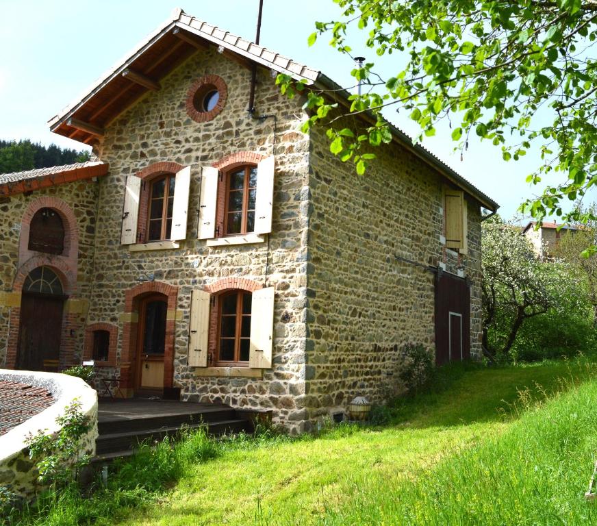 una vecchia casa in pietra in un prato erboso di La Fabrique du Ronçon a Saint-Bonnet-le-Troncy
