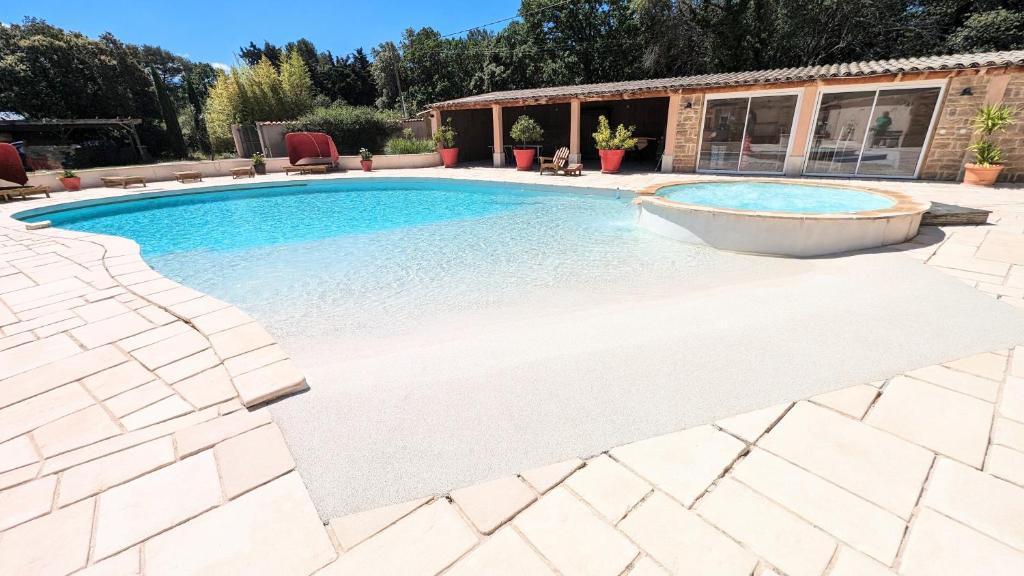 - une piscine dans un jardin avec une terrasse en pierre dans l'établissement Villa l'Escargolette avec piscine privée, à Carpentras
