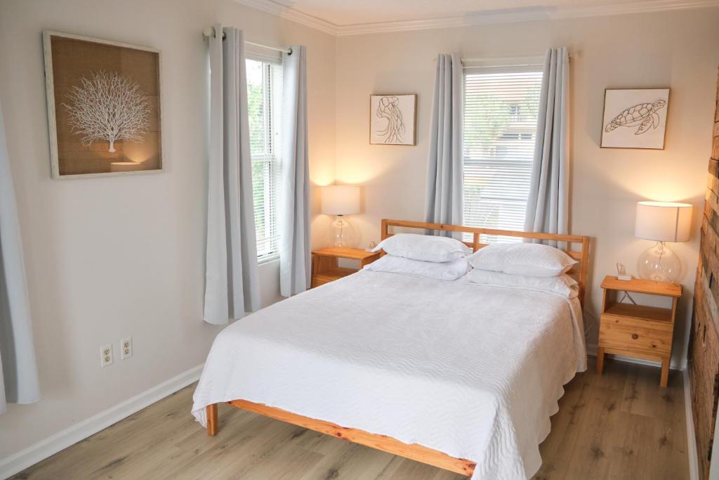 - une chambre avec un lit blanc et 2 fenêtres dans l'établissement Two Bedrooms - Walk to the Beach!, à Jacksonville Beach