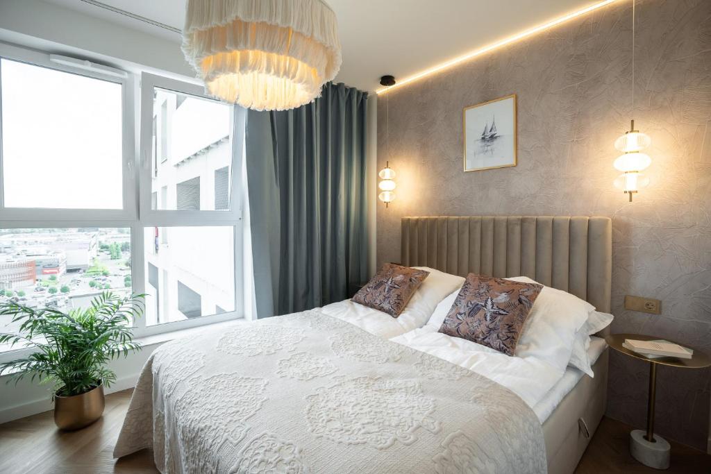 - une chambre avec un lit blanc et une grande fenêtre dans l'établissement KOBIELA APARTMENTS Dębowe Tarasy, à Katowice