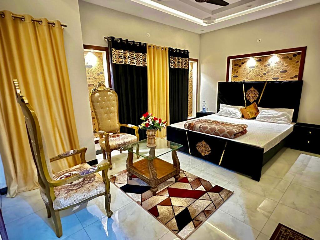 a bedroom with a bed and a chair and a table at Homely Guest House in Rawalpindi
