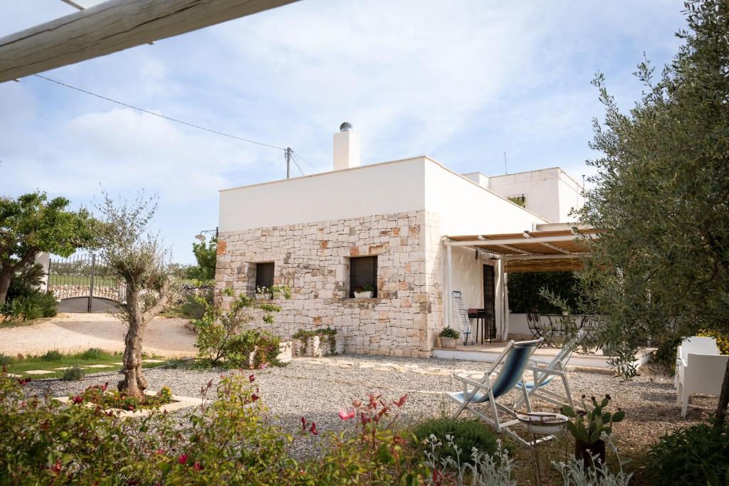 une maison blanche avec deux chaises dans un jardin dans l'établissement Il Trullo Volza, à Locorotondo