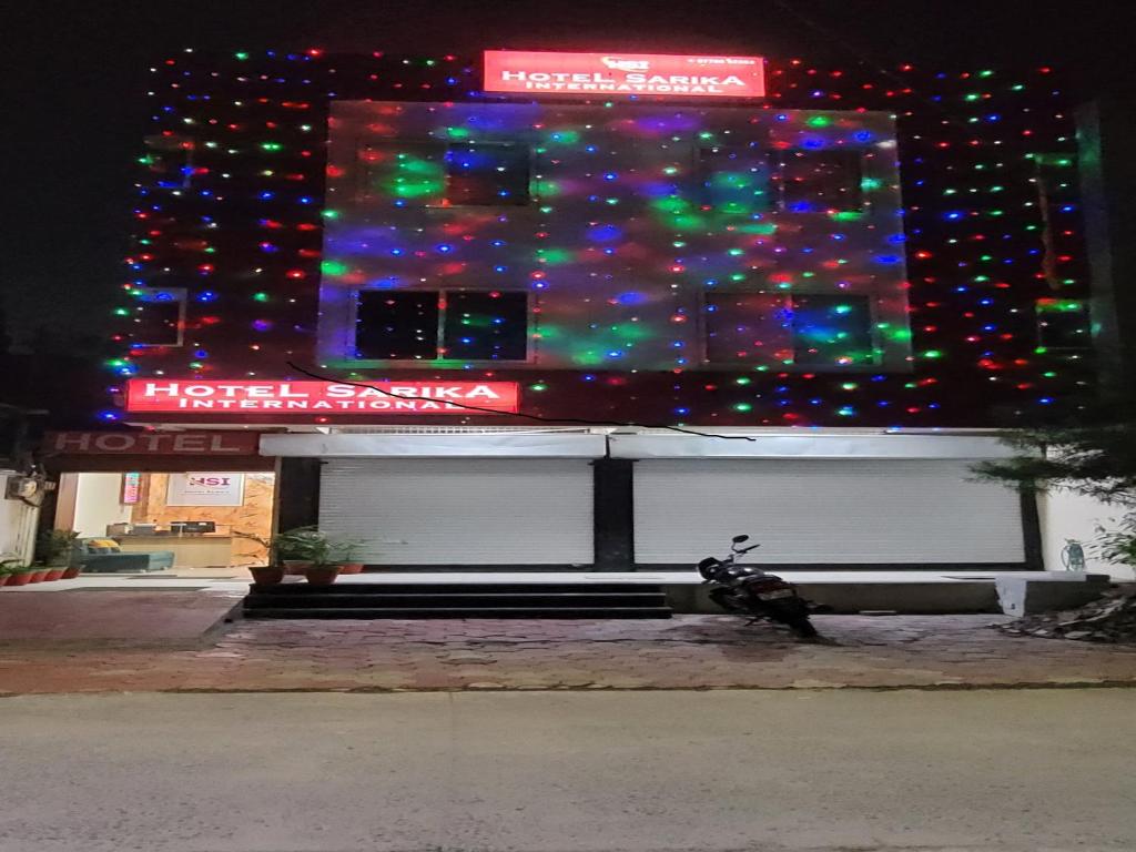 Una motocicleta estacionada frente a un edificio con luces de Navidad en Hotel Sarika International, en Indore