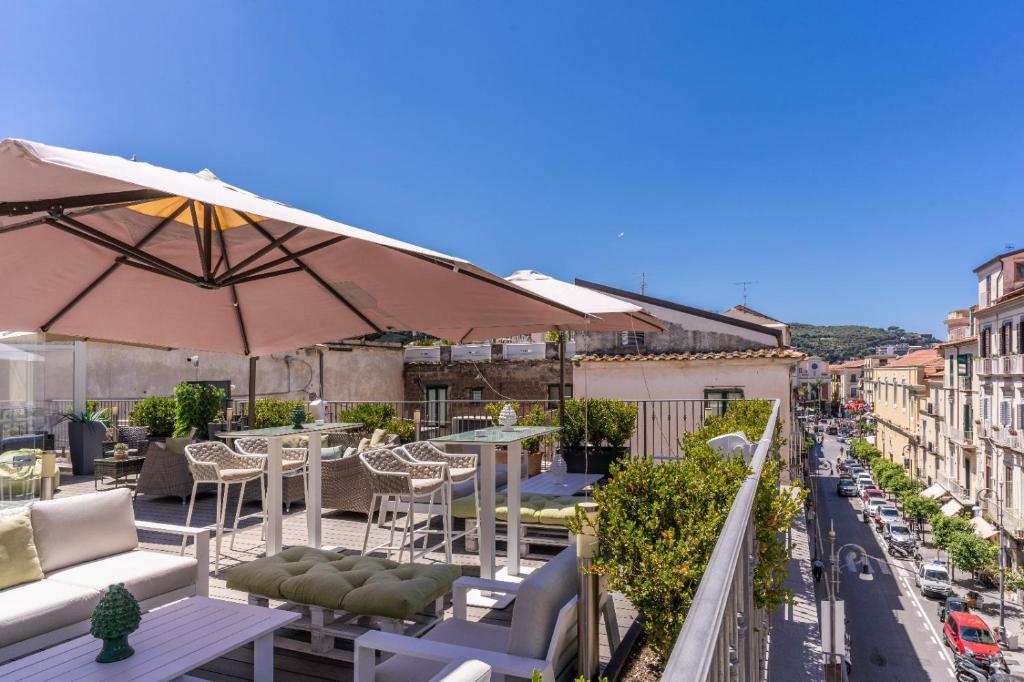 einen Balkon mit Tischen, Stühlen und einem Sonnenschirm in der Unterkunft Hotel Sorrento City in Sorrent