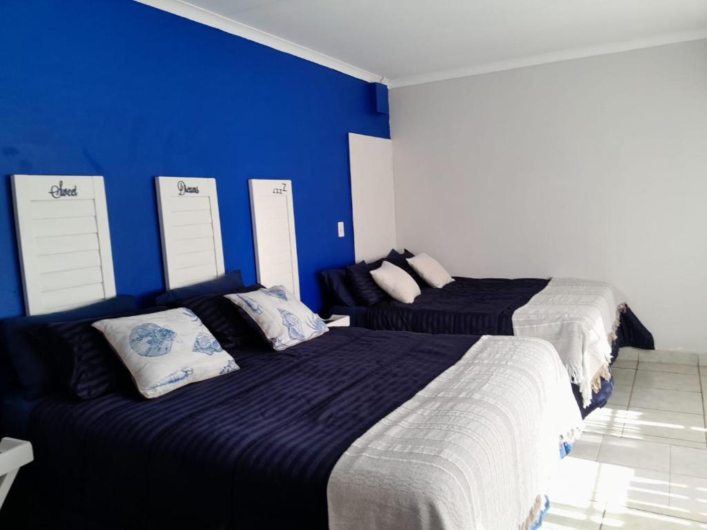 2 łóżka w pokoju z niebieską ścianą w obiekcie Sweet Dreams Polokwane w mieście Polokwane
