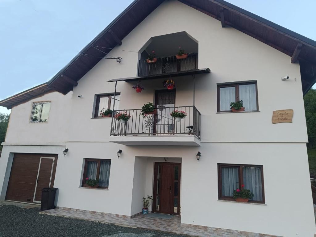 una casa blanca con macetas en los balcones en Casuta Din Livada, en Moisei