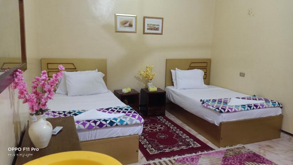 a hotel room with two beds and a vase of flowers at Amon guest house in Abu Simbel