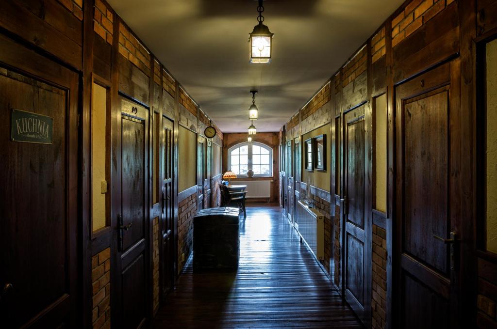 Dim rustic corridor lined with wooden doors, hanging lanterns, polished floor and trunk.