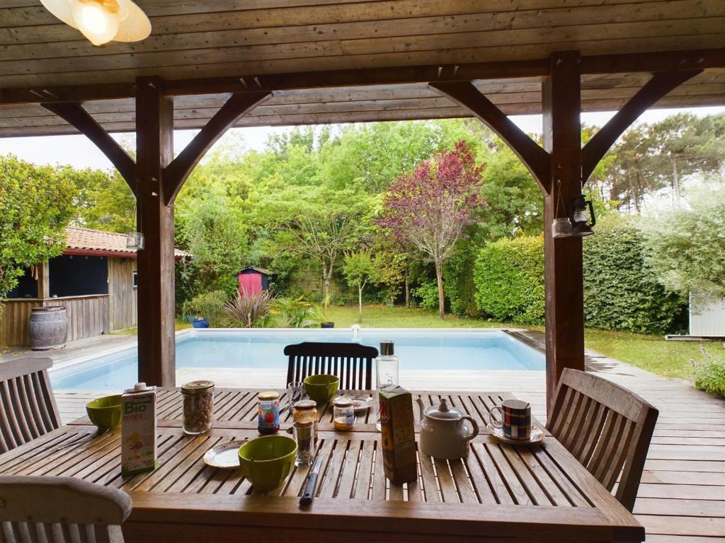 une table en bois sur une terrasse à côté d'une piscine dans l'établissement Piscine et sérénité pour votre séjour à Lanton, à Lanton