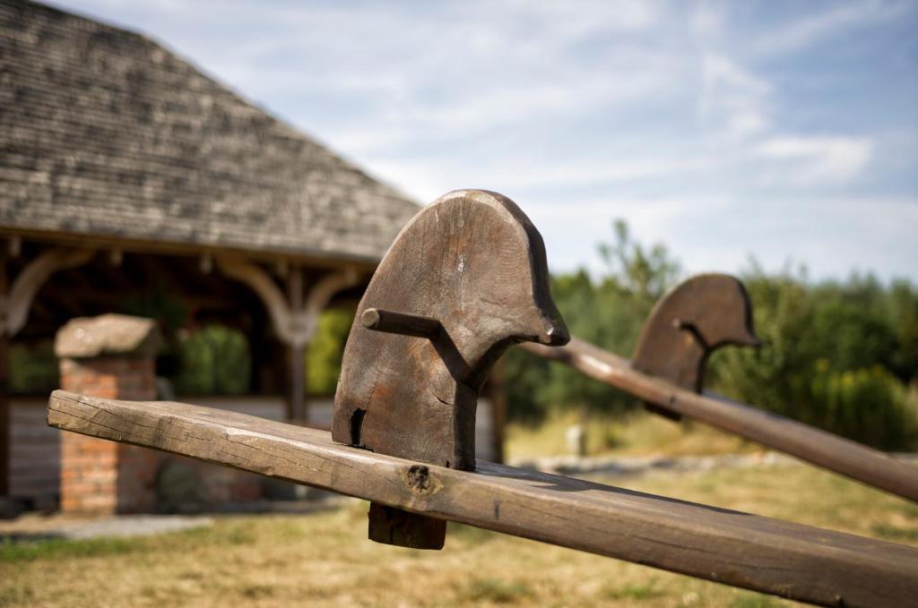 Close-up of weathered wooden seesaw handles outside near timber pavilion and grassy area.