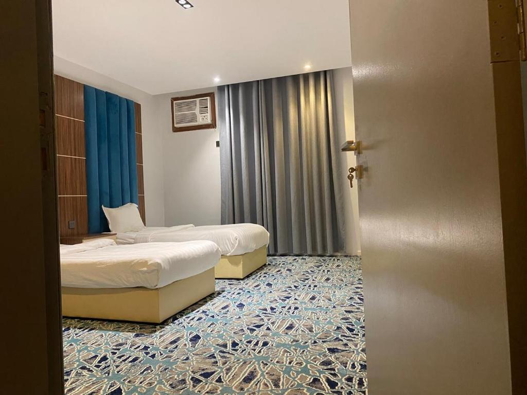 two beds in a hotel room with a door open at كيان ألين in Abha