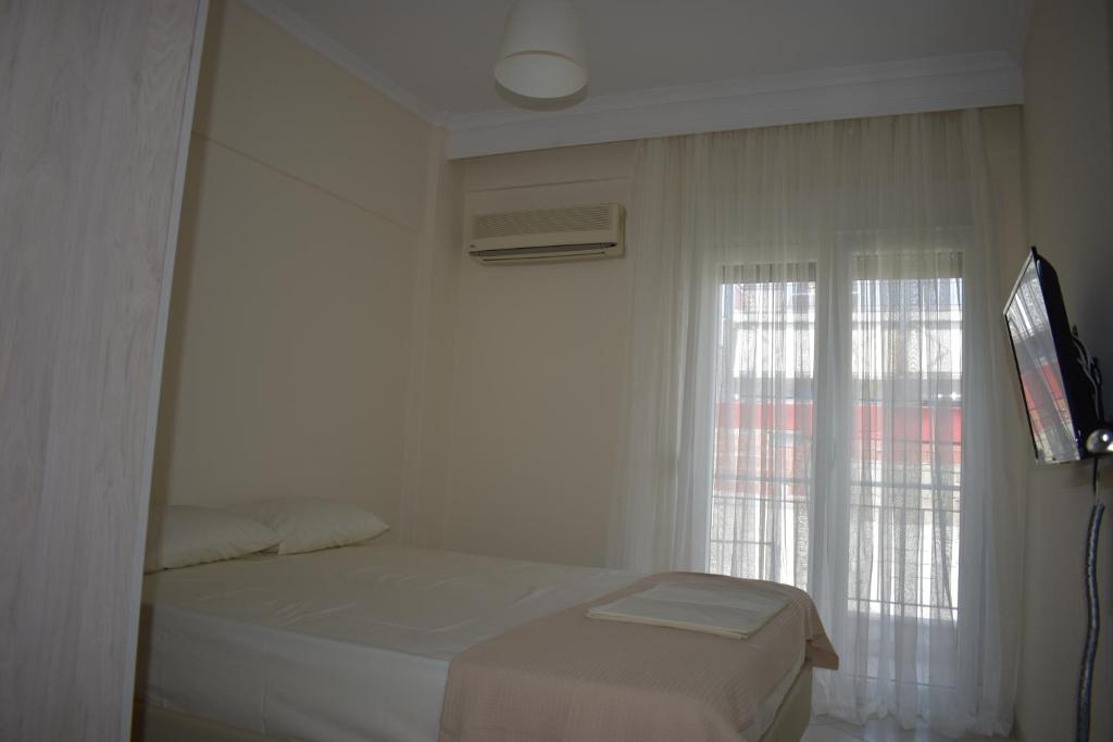 a white bedroom with a bed and a window at By The Sea in Asprovalta