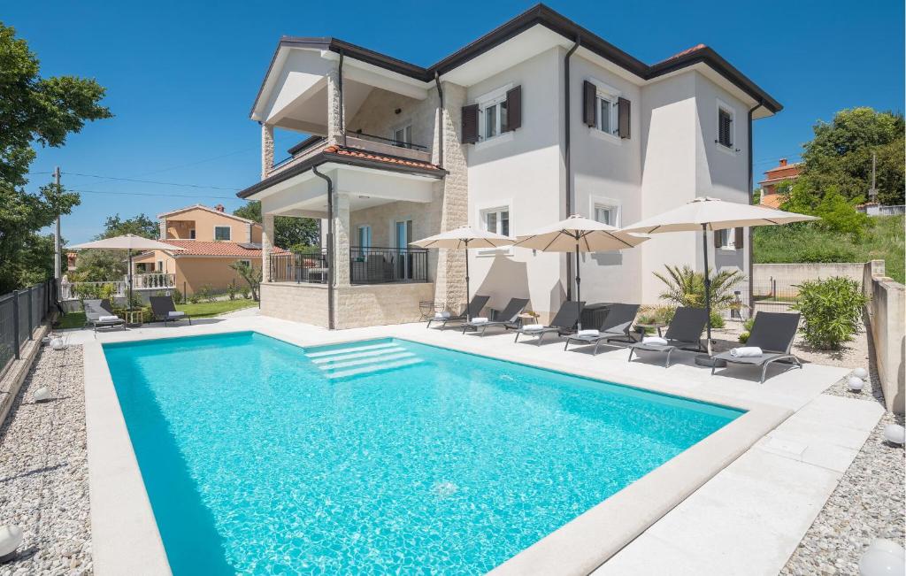 - une piscine en face d'une maison avec des parasols dans l'établissement Gorgeous Home In Rojci With Kitchen, à Kaštelir