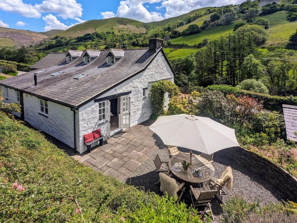a house with an umbrella and a table and chairs at Tyn Y Ffordd in Llanymawddwy