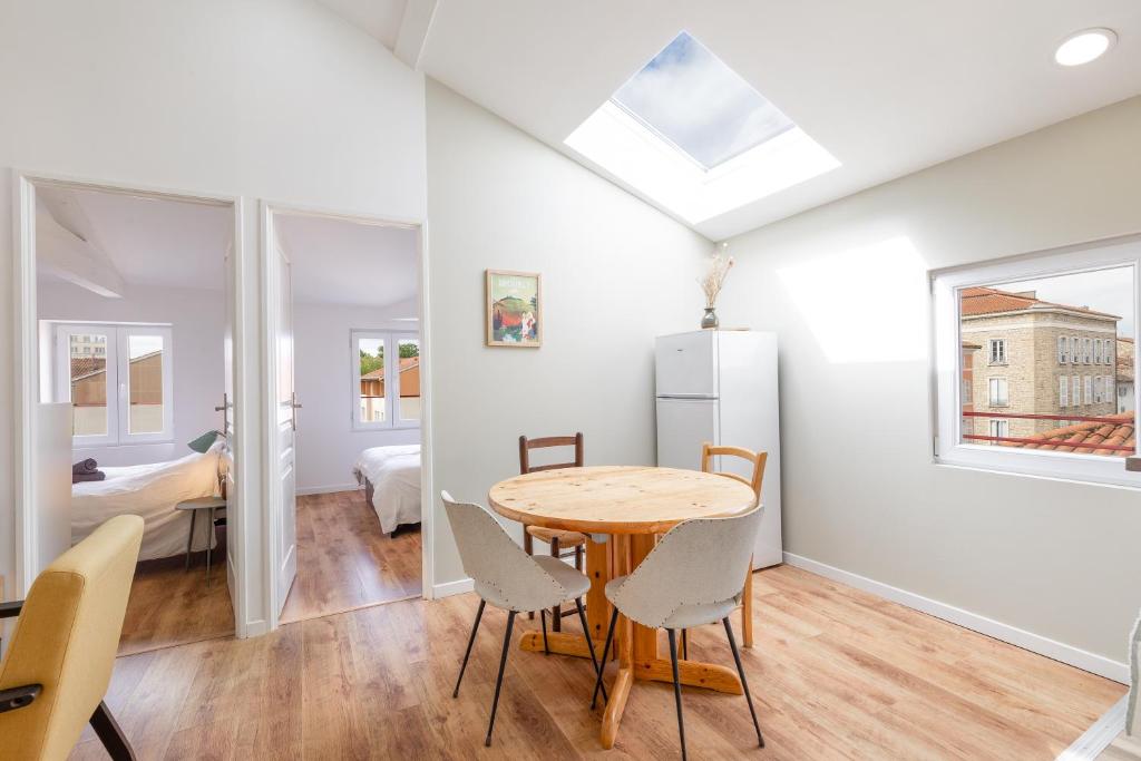 cocina y comedor con mesa y sillas en Appartement climatisé 2 chambres en Villefranche-sur-Saône