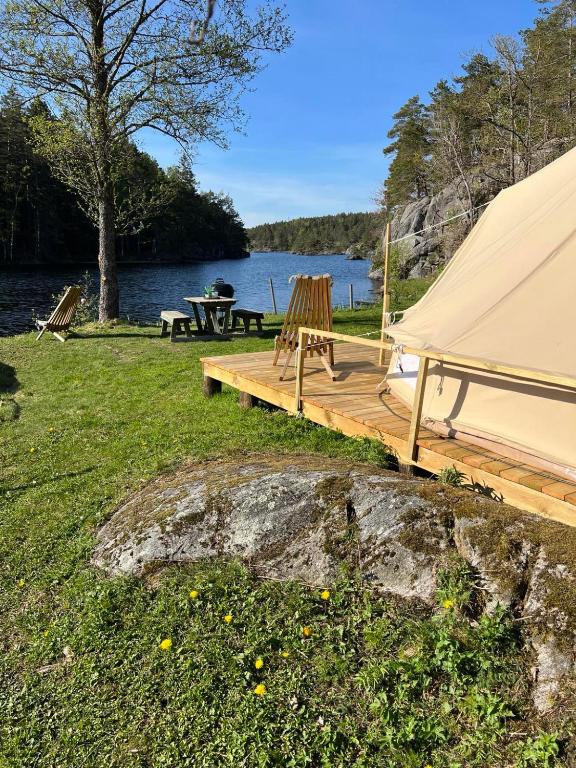 a wooden deck with a tent and a picnic table at Hommen Gård Glamping in Risør
