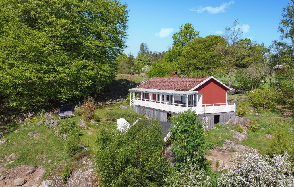 une maison rouge et blanche sur une colline plantée d'arbres dans l'établissement Cozy Home In Hkerum With Kitchen, à Hökerum
