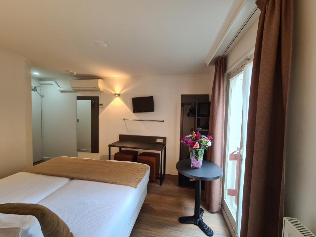 アムステルダムにあるアベニュー ホテルのベッドと花のテーブルが備わるホテルルームです。