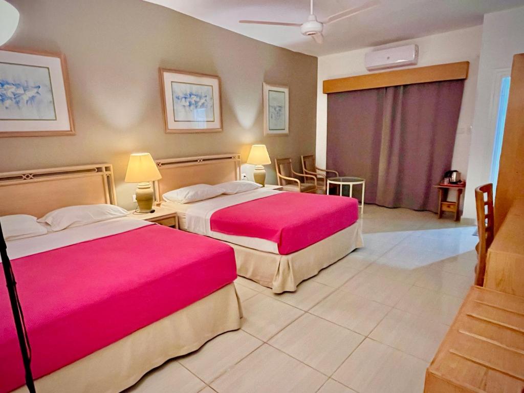 ハルガダにあるMasaya Hurghada Roomsのピンクのシーツが備わるベッド2台が備わるホテルルームです。