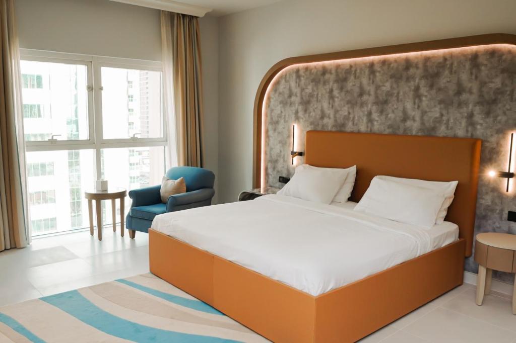 Sheraton Khalidiya Hotel في أبوظبي: غرفة نوم بسرير كبير وكرسي ازرق