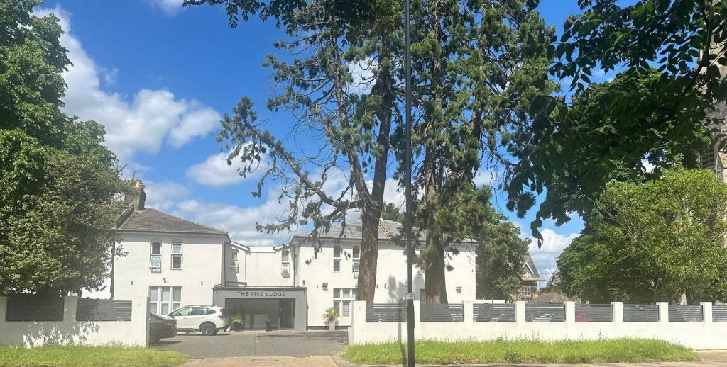 a white building with a car parked in front of it at The Firs Lodge in Hounslow