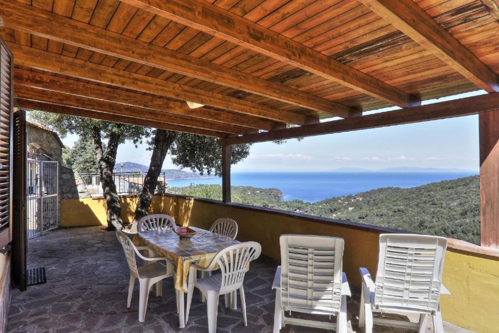 a patio with a table and chairs and the ocean at Casa Ilva - Colle Paradiso Experience in Capoliveri