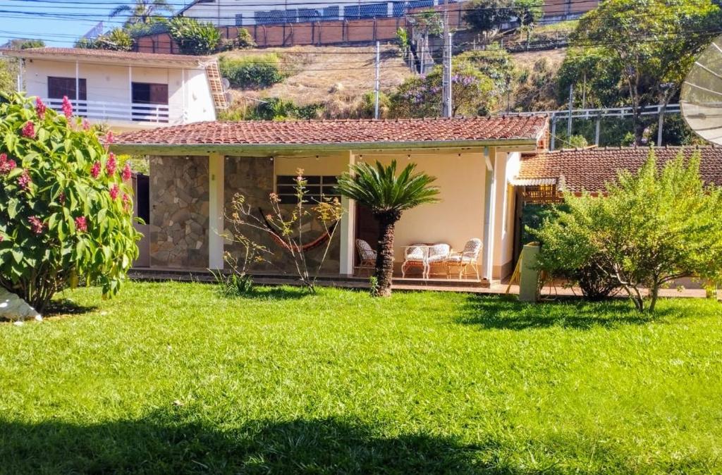 een klein huis met een groene tuin bij Recanto Jacarandá in Ouro Fino