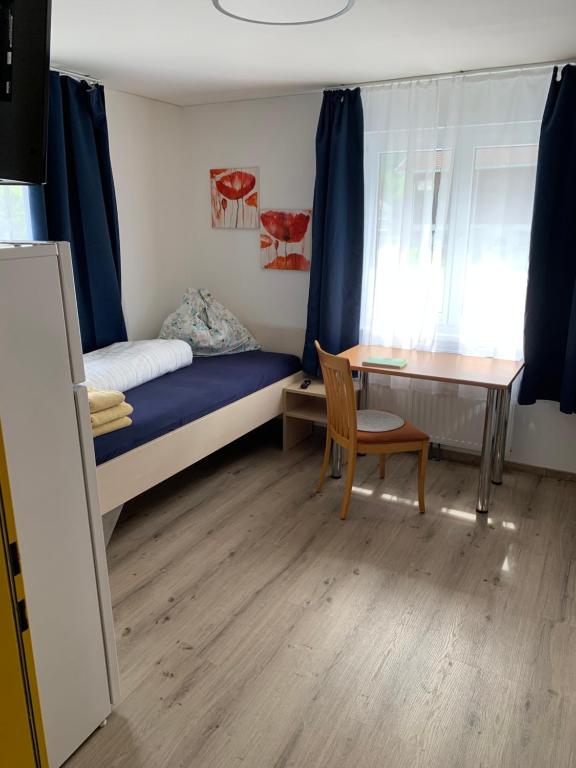 a bedroom with a bed and a desk and a table at Kleine drei Länderzentrale in Hohenems