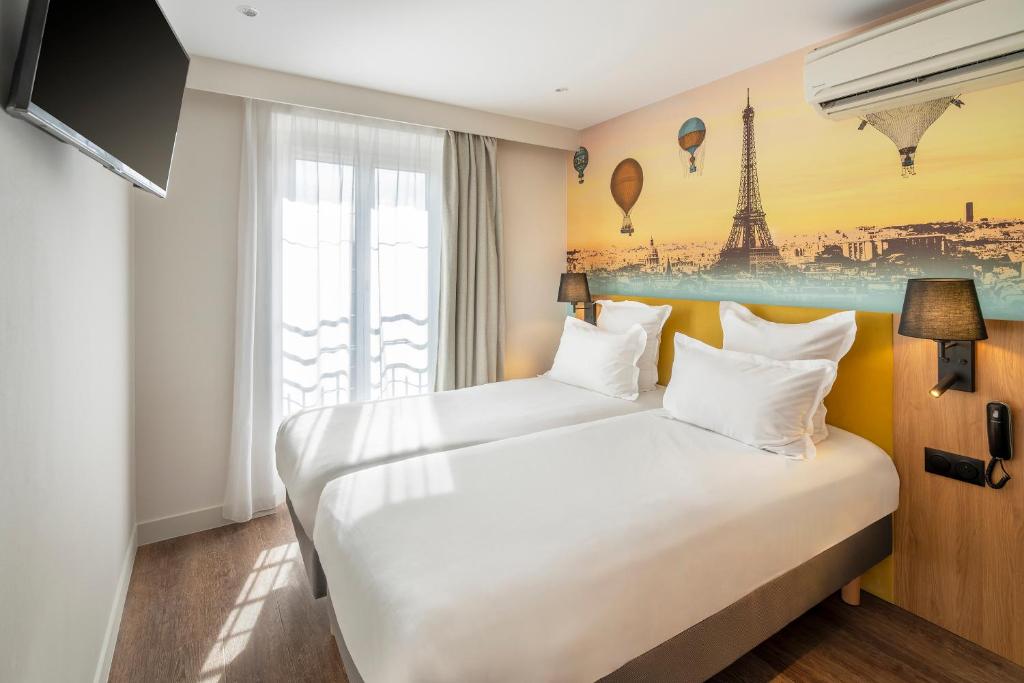 two beds in a hotel room with a view of the eiffel tower at Hotel Apolonia Paris Mouffetard, Sure Hotel Collection by Best Western in Paris