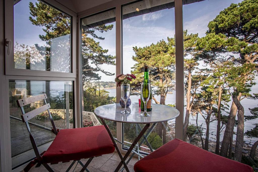 une table et deux chaises dans une pièce avec des fenêtres dans l'établissement La loge, La Loge House overlooking the sea in Per, à Perros-Guirec