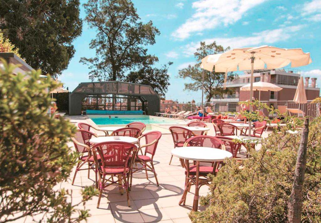 un patio con tavoli e sedie accanto alla piscina di Hotel San Giuseppe a Finale Ligure