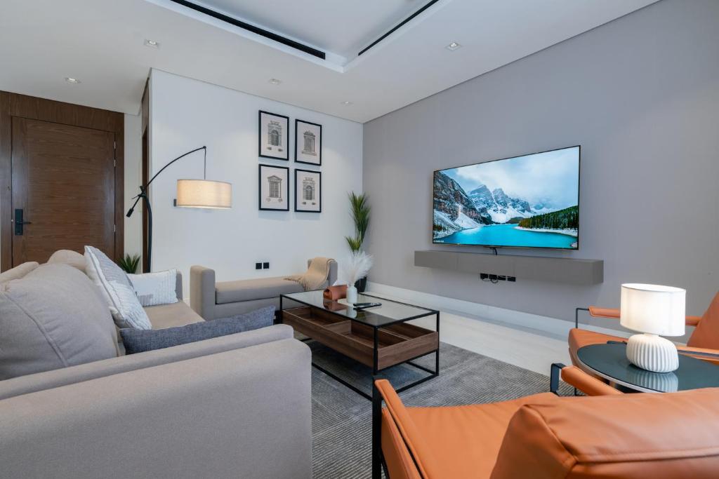 a living room with a couch and a tv on a wall at أكاريم الملقا Akareem AL-Malqa in Riyadh