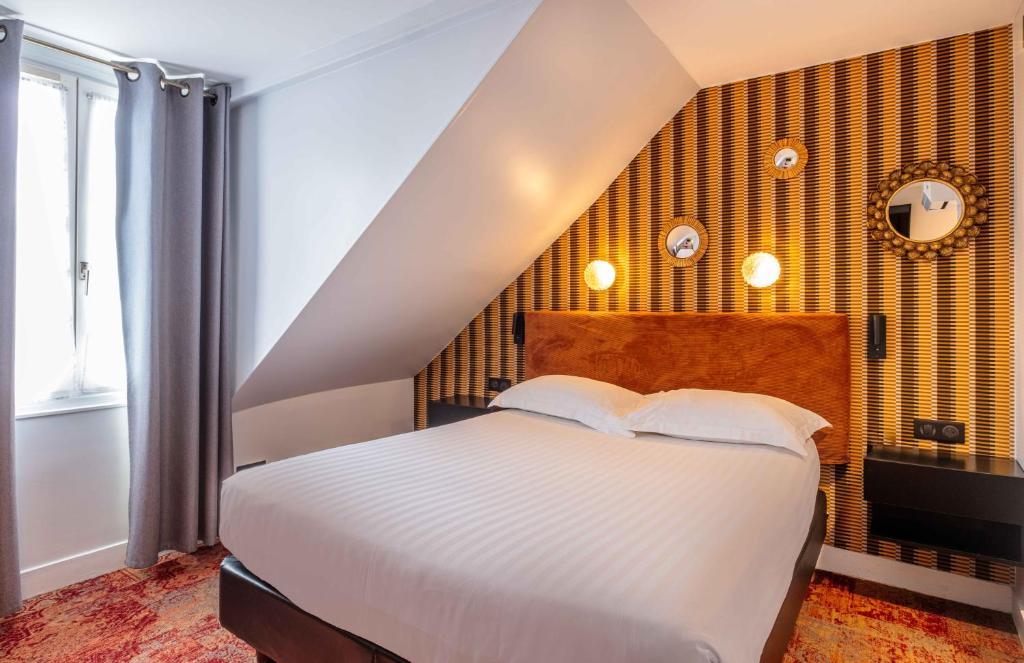 una camera con un letto bianco e una parete gialla di Hotel Marena a Parigi