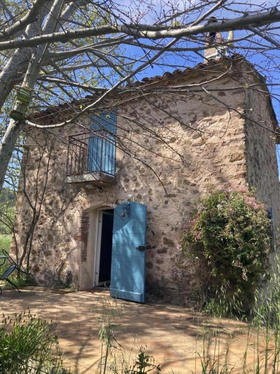 une maison en pierre avec une porte bleue et une fenêtre dans l'établissement Gîte Superbe Bastidon Provençal isolé au cœur des vignes Bio, à Cuers