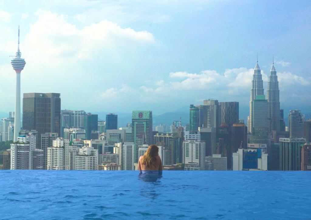 een vrouw in het overloopzwembad met uitzicht op een stad bij Harmony Luxury Suites At Lucentia Bukit Bintang City Center in Kuala Lumpur