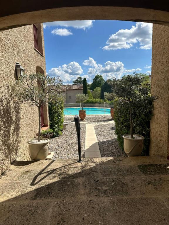een binnenplaats met twee potbomen en een zwembad bij Le Mas de l'Orangerie 3 etoiles in Gréoux-les-Bains
