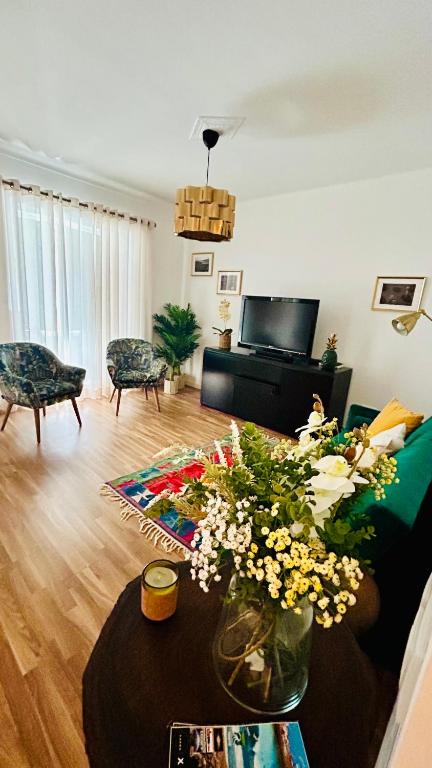 a living room with a couch and a table with flowers at Salty Home’s in Peniche