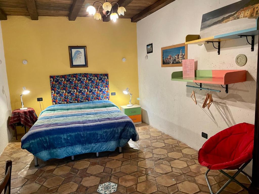 ein Schlafzimmer mit einem Bett und einem roten Stuhl in der Unterkunft Le Petit Chateau in Vezzi Portio