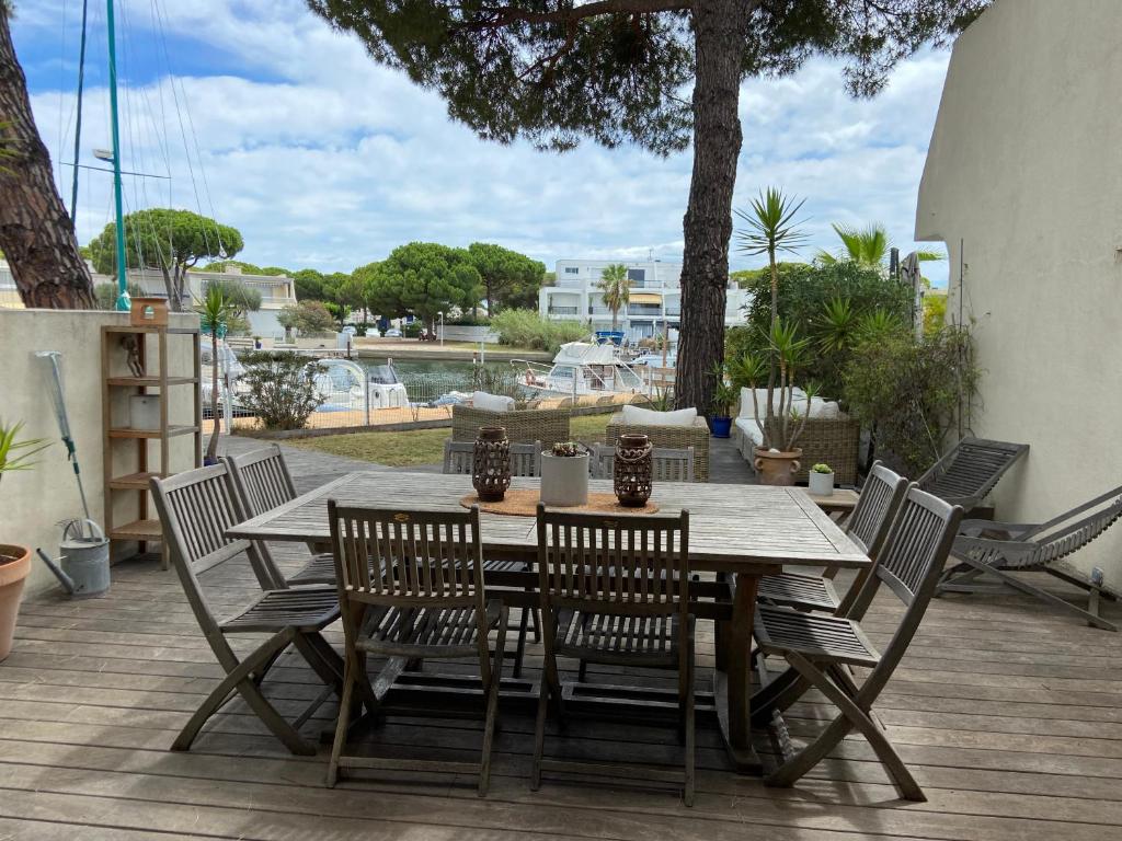 une table et des chaises en bois sur une terrasse dans l'établissement Marina avec place de bateau à port Camargue, au Grau-du-Roi