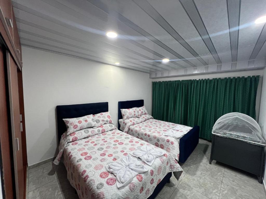 een slaapkamer met 2 bedden en een groen gordijn bij Villa del Centro in Paipa