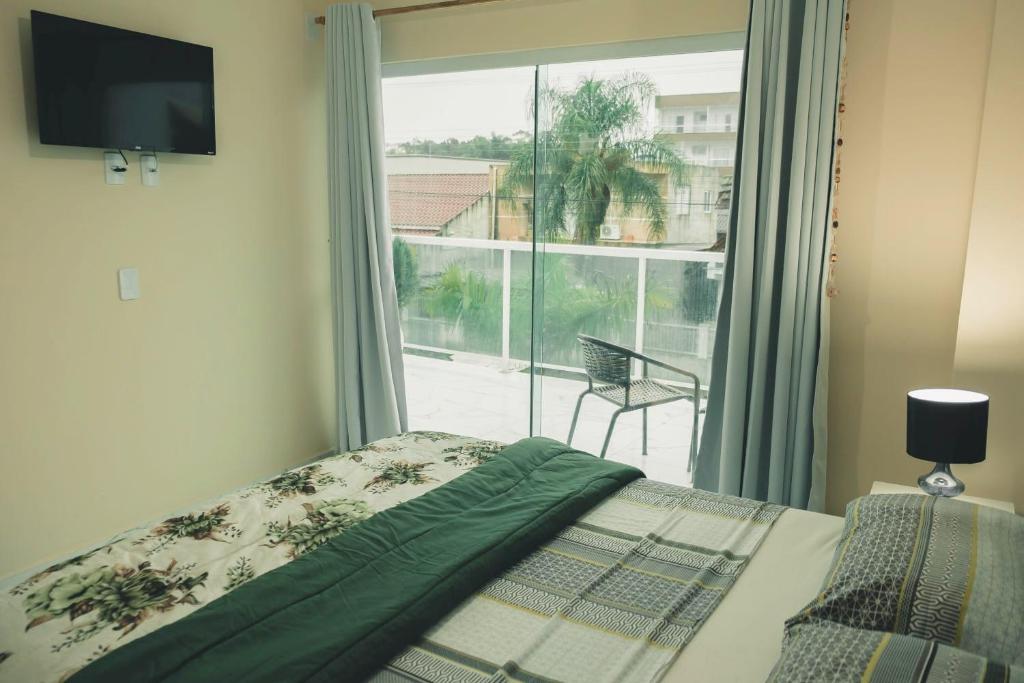 a bedroom with a bed and a large window at Pousada Cavalero in Penha