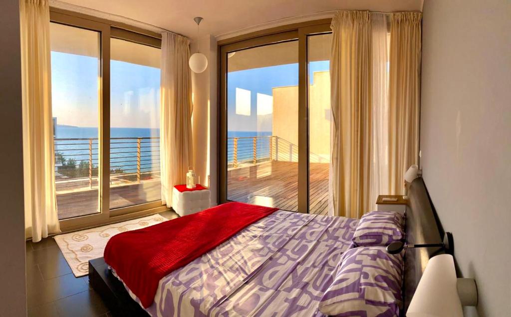 a bedroom with a bed and a balcony with the ocean at Sea view Penthouse (YooBulgaria) in Obzor