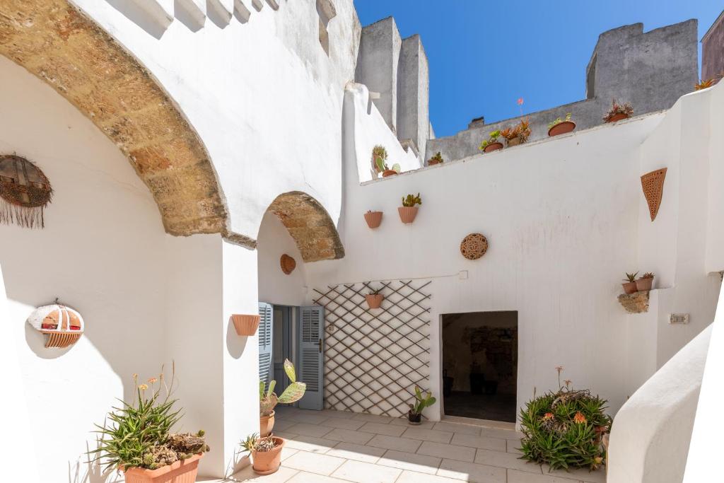 a courtyard of a house with white walls and potted plants at 10 minuti dalla spiaggia, Elegante Villa in Ugento