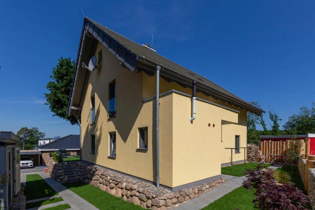 une maison jaune avec un mur en pierre dans l'établissement Fewo Südstrand mit Terrasse, Kamin und Sauna, à Sellin