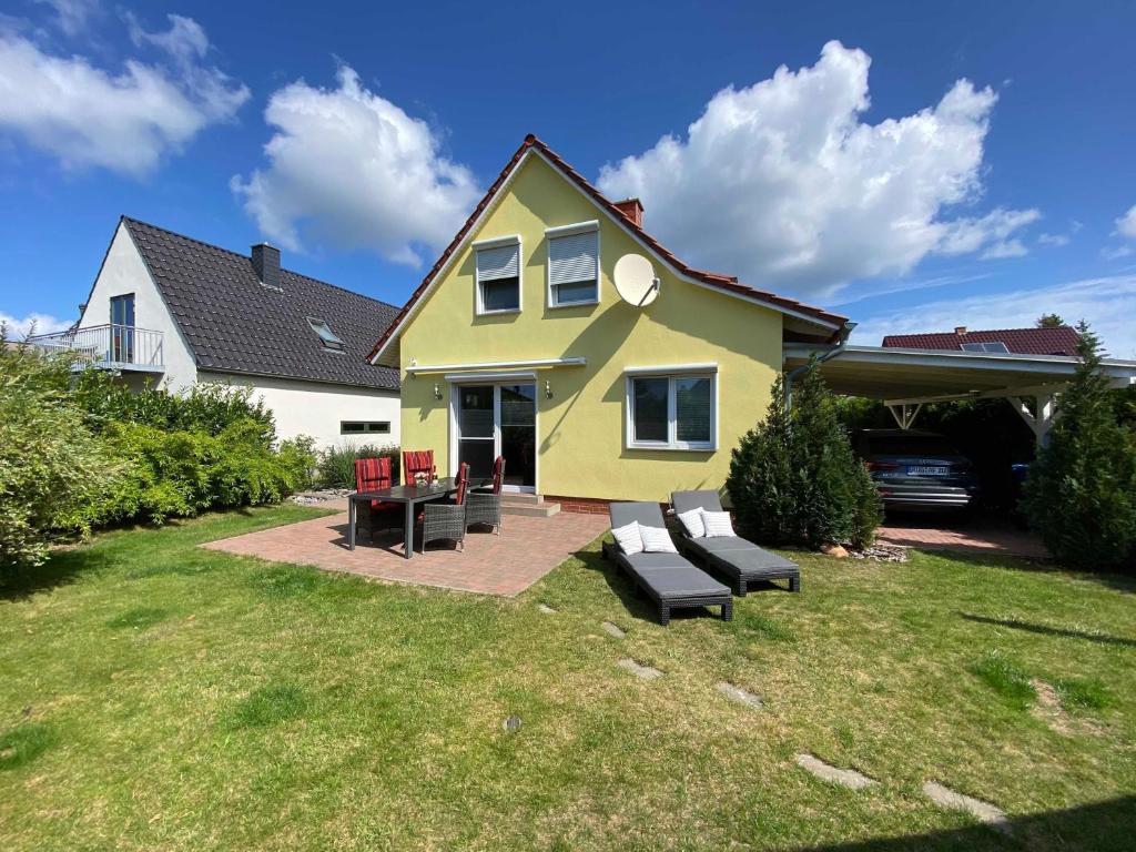 een geel huis met een patio in de tuin bij Ferienhaus Uns lütt Hus mit Sauna in Baabe