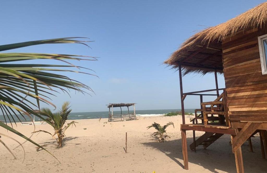 a hut on a beach with the ocean at Bosofet Beach and Creek Lodge in Sanyang