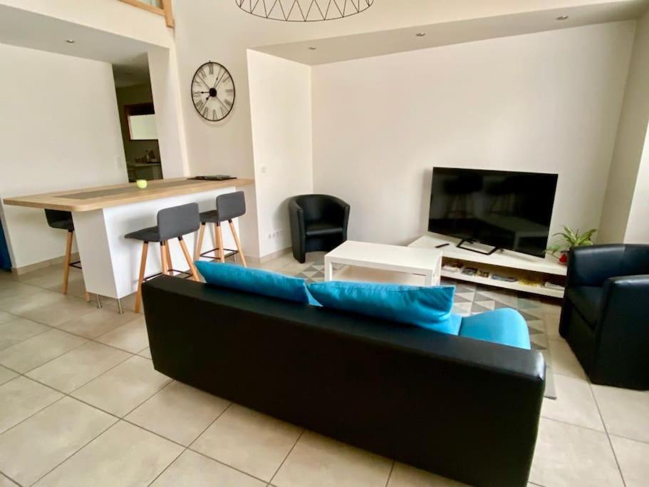 un salon avec un canapé noir et une table dans l'établissement Appartement Duplex 3 chambres - La Blache des Collines, à Beausemblant