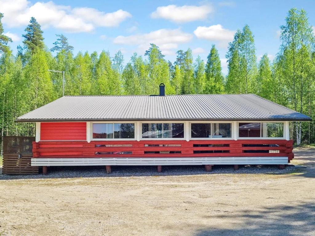 una casa rossa con un tetto di metallo su un campo di Holiday Home Minervahovi by Interhome a Pääjärvi