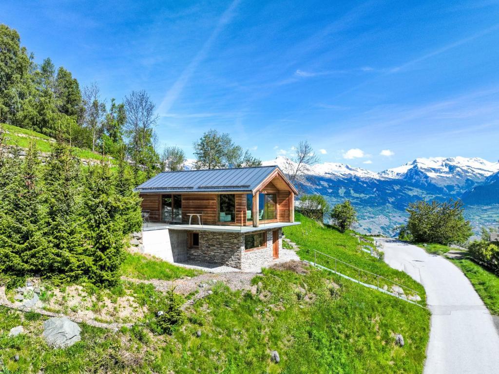 a wooden house on a hill with a road at Chalet Papillon by Interhome in Nendaz